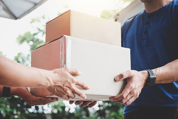 a person handing two parcels to a delivery courier