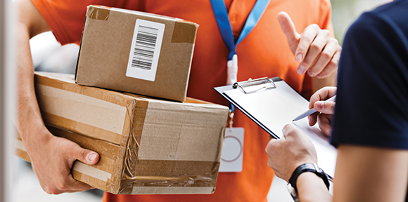 a courier asking someone to sign a parcel with two parcels under his right arm