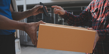 a courier showing a mobile device for a business owner to sign for a parcel